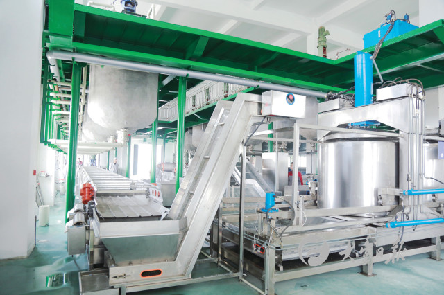 医药科技有限公司生产车间内,工人正操作机器生产甲壳生物多糖原料